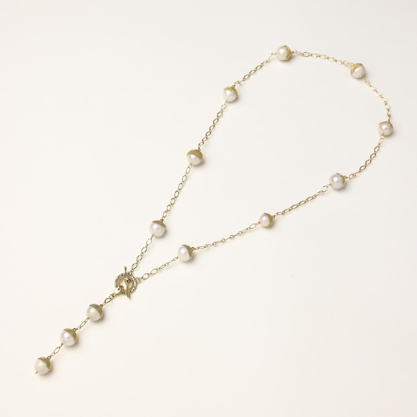 Long gold-plated lariat necklace featuring baroque pearls with metal caps arranged in elegant Y-shape design
