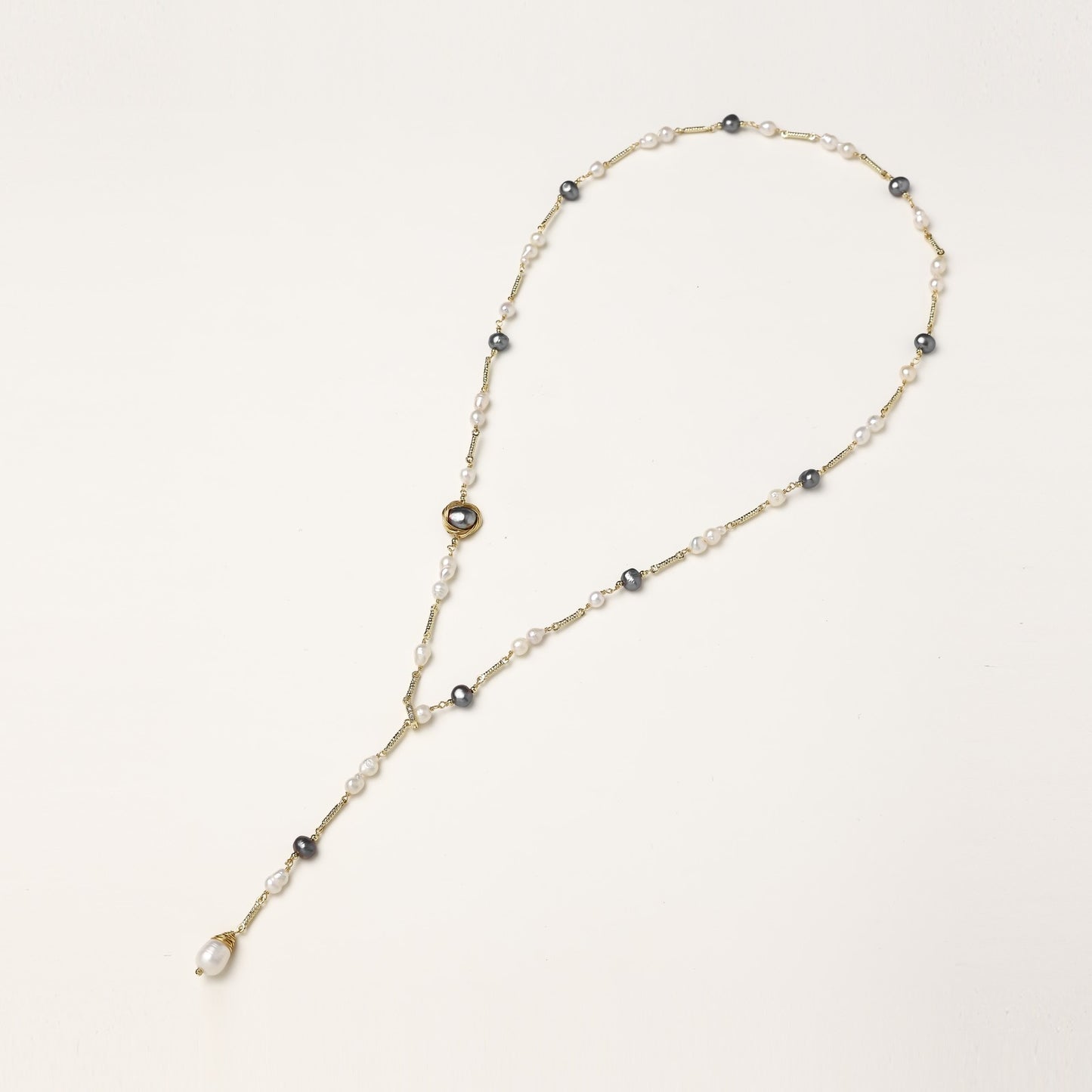 Long gold-plated necklace with alternating white and gray freshwater pearls spaced along delicate chain segments