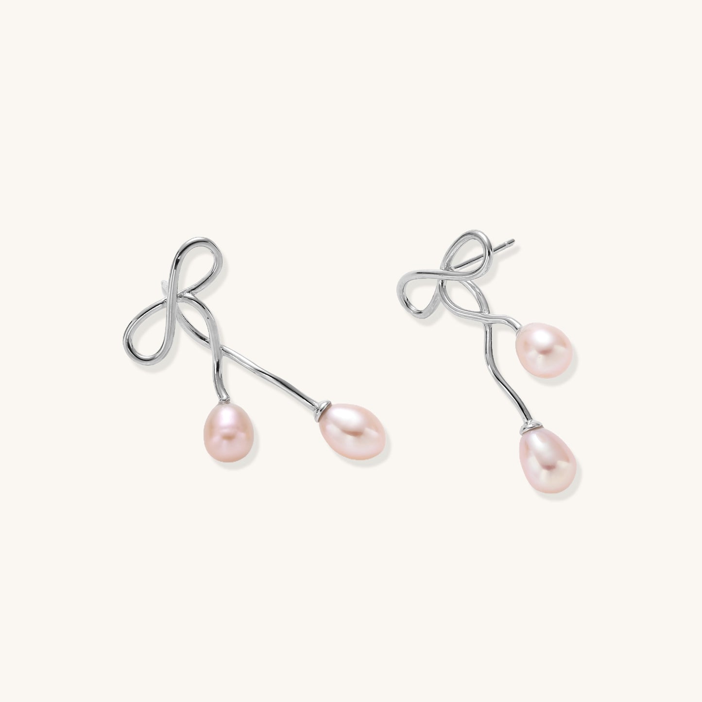 Delicate sterling silver wire earrings with organic bow shapes and two pink freshwater pearls on white background