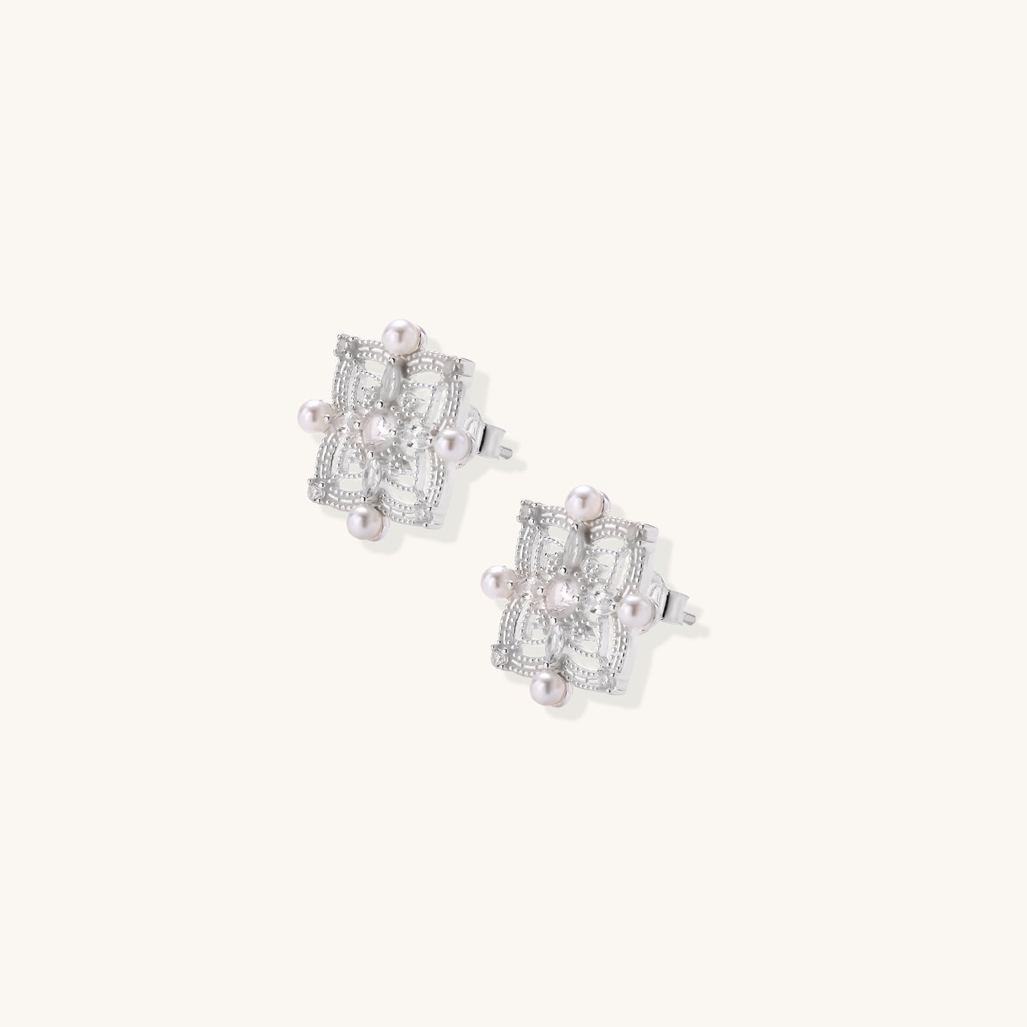 Detailed view of sterling silver stud earrings with geometric filigree design and small freshwater pearls on white background.