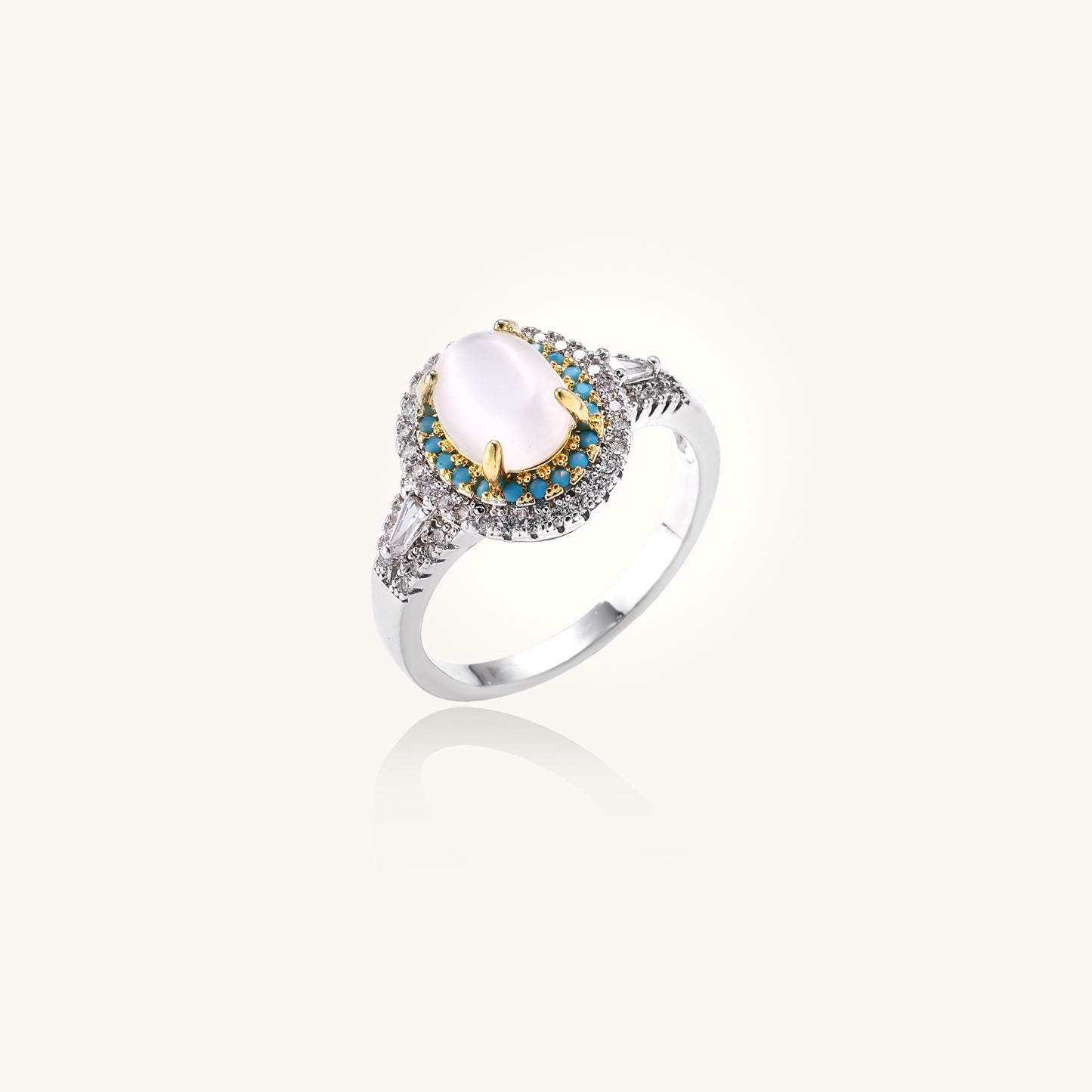 Gold-plated ring with oval cat's eye stone center, blue accent stones, and crystal halo on white background.