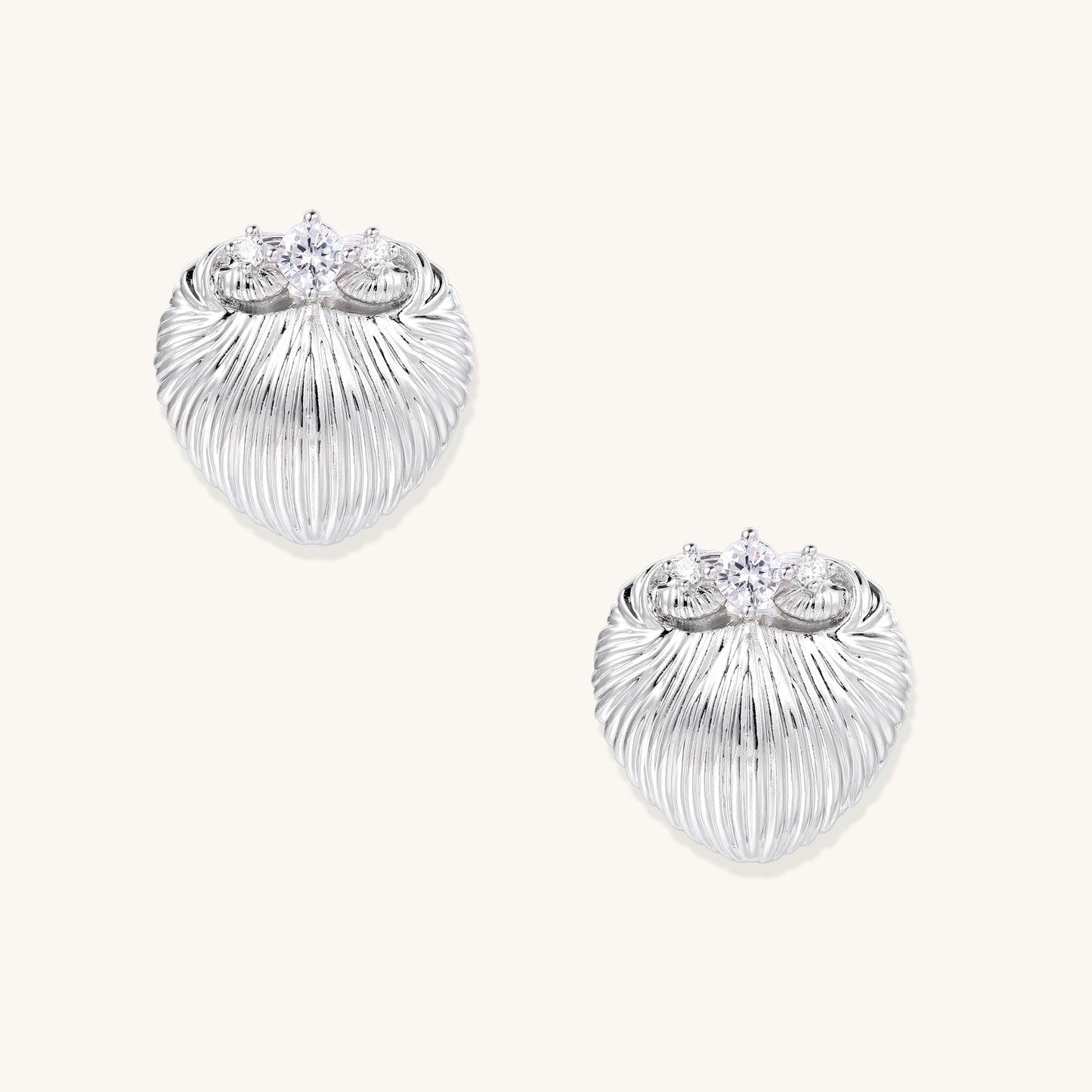 Pair of gold-plated heart-shaped earrings with vertical ribbed texture and sparkling zirconia stones at top on white background.