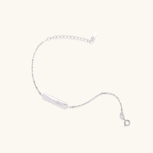 Minimalist bracelet with iridescent baroque pearl on rhodium-plated sterling silver chain against cream background