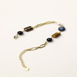 Gold-plated chain bracelet featuring tiger's eye, obsidian, freshwater pearls and abalone shell on white background