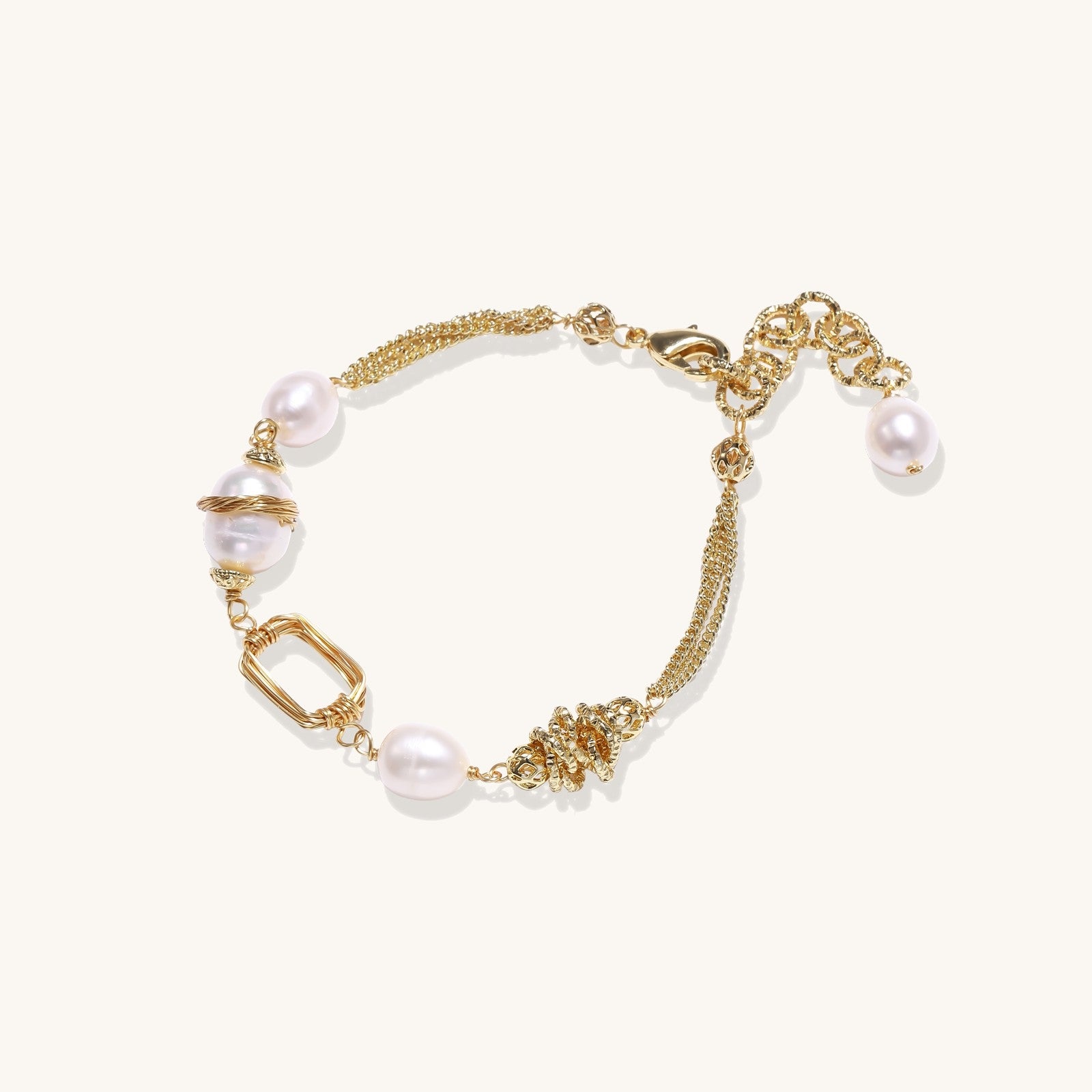 Gold-plated bracelet featuring cream freshwater pearls and decorative chain links on white background.