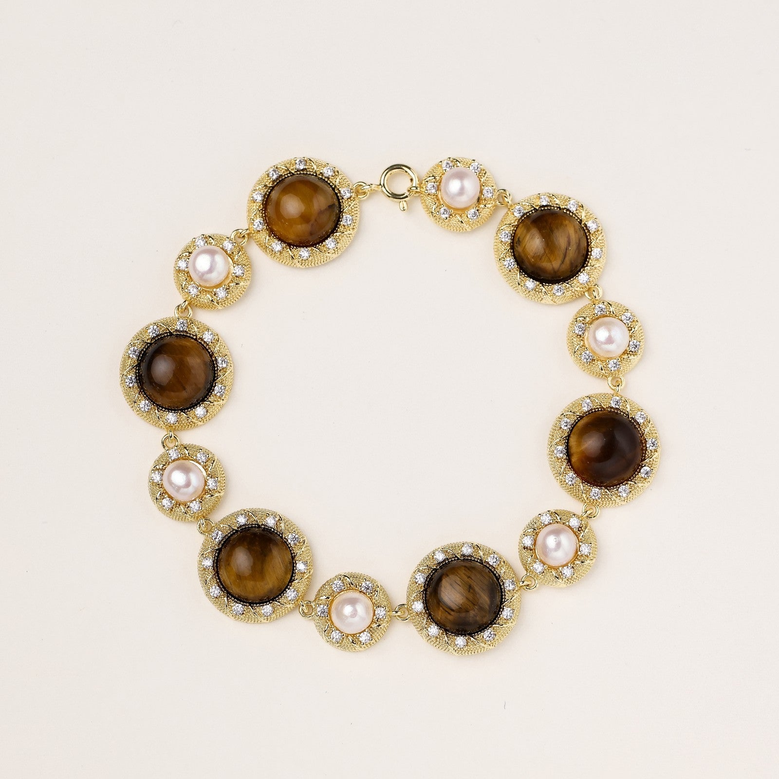 Ornate gold-plated bracelet with alternating brown tiger's eye stones and white freshwater pearls in crystal-accented settings