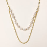 Layered gold chain necklace with irregular freshwater pearls on cream background, showing adjustable dual-strand design.