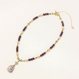 Gold-plated necklace with purple amethyst beads, pink pearls, and iridescent baroque pearl pendant beneath crystal star charm