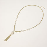 Layered gold-plated necklace with freshwater pearls, central pearl cluster, and chain tassel on cream background.