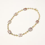 Long gold-plated necklace with iridescent baroque pearls and round freshwater pearls on cream background