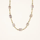 Long gold-plated necklace with iridescent baroque pearls and round freshwater pearls on cream background