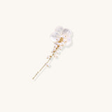 Delicate hair pin featuring translucent shell flower with cascading freshwater pearls on gold chain against cream background.
