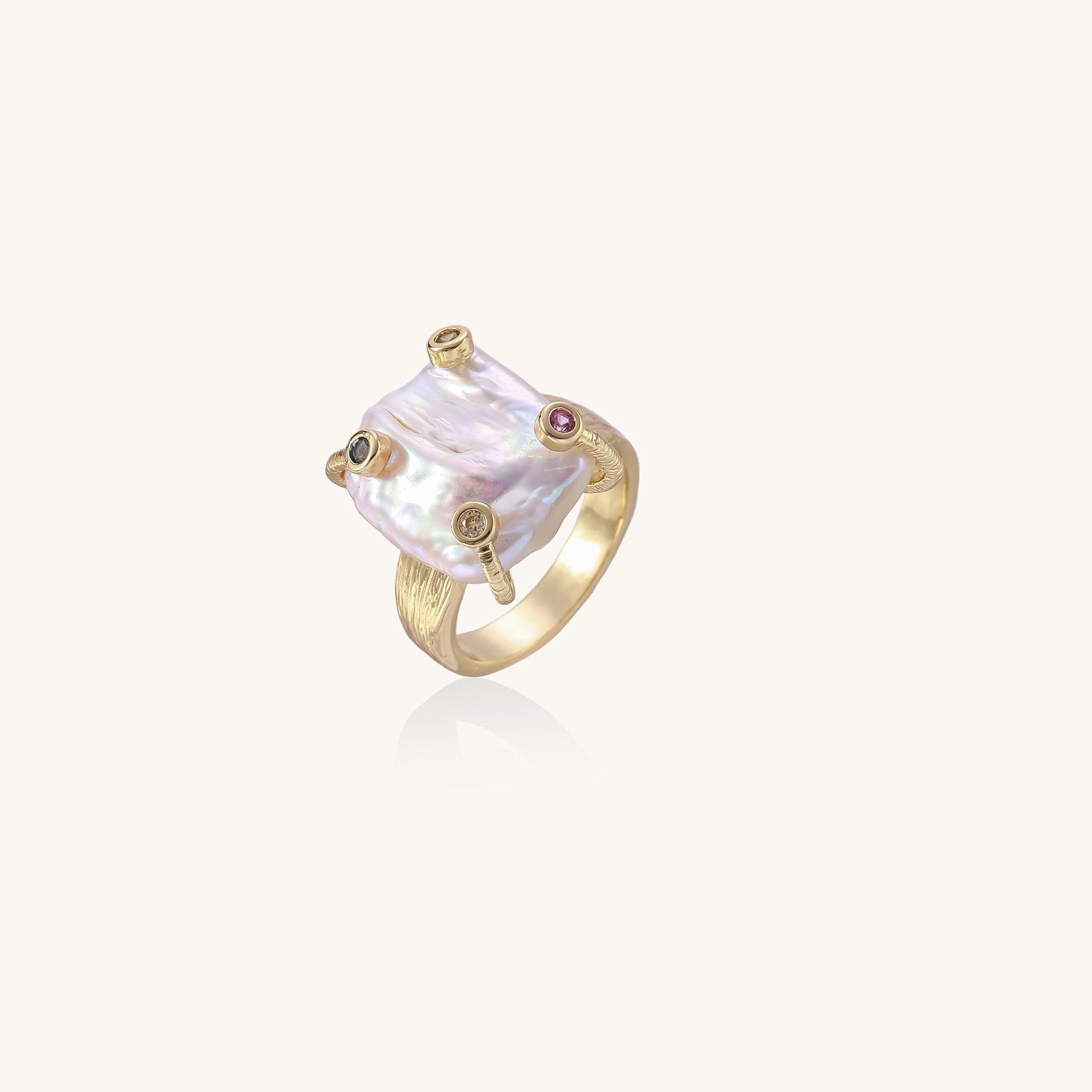 Gold-plated ring featuring large baroque freshwater pearl with small colorful gemstone accents on textured band