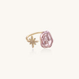 Adjustable ring with lavender baroque pearl and crystal star charm on gold-plated band against cream background.