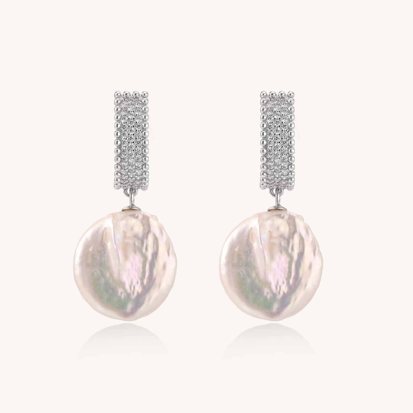 Sterling silver huggie earrings with lustrous baroque pearls displaying iridescent pink and cream tones on white background.