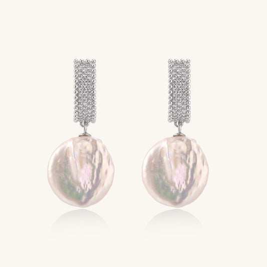 Sterling silver huggie earrings with lustrous baroque pearls displaying iridescent pink and cream tones on white background.