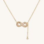 Delicate 14K gold plated infinity pendant with crystal accents on adjustable chain with small ball charm detail.