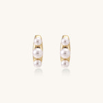 Delicate gold stud earrings with three lustrous white freshwater pearls arranged in an organic curved line.