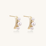 Delicate gold stud earrings with three lustrous white freshwater pearls arranged in an organic curved line.