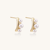 Delicate gold stud earrings with three lustrous white freshwater pearls arranged in an organic curved line.