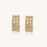 Close-up of geometric gold-plated hoop earrings with crystal pave in intricate lattice pattern on neutral background.