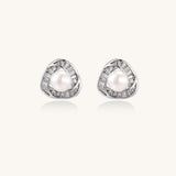 Close-up of triangular gold-plated stud earrings with central freshwater pearl surrounded by baguette crystals