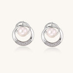 Gold-plated brass stud earrings with swirled circular design holding white freshwater pearls and small crystals
