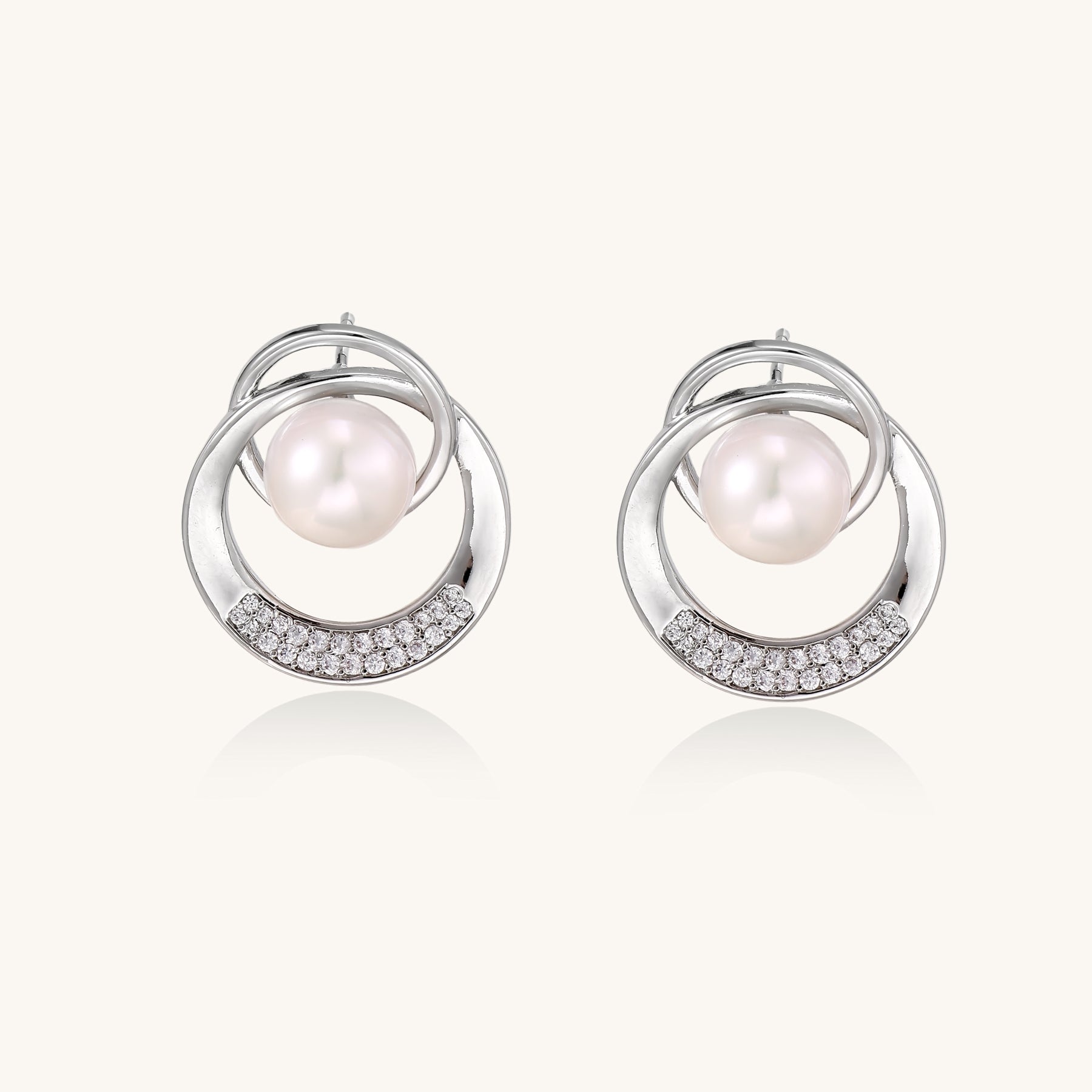 Gold-plated brass stud earrings with swirled circular design holding white freshwater pearls and small crystals