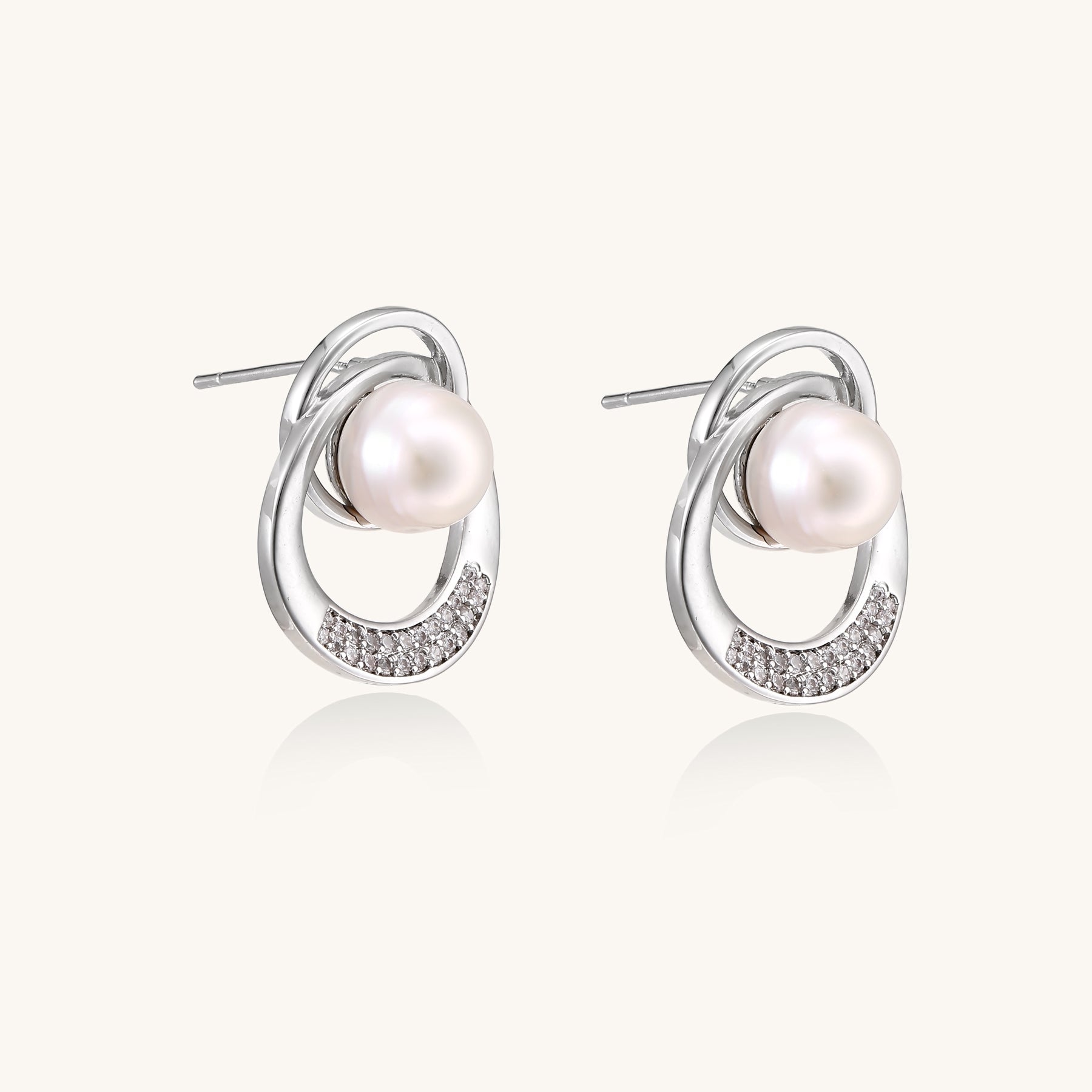 Gold-plated brass stud earrings with swirled circular design holding white freshwater pearls and small crystals