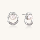 Gold-plated brass stud earrings with swirled circular design holding white freshwater pearls and small crystals