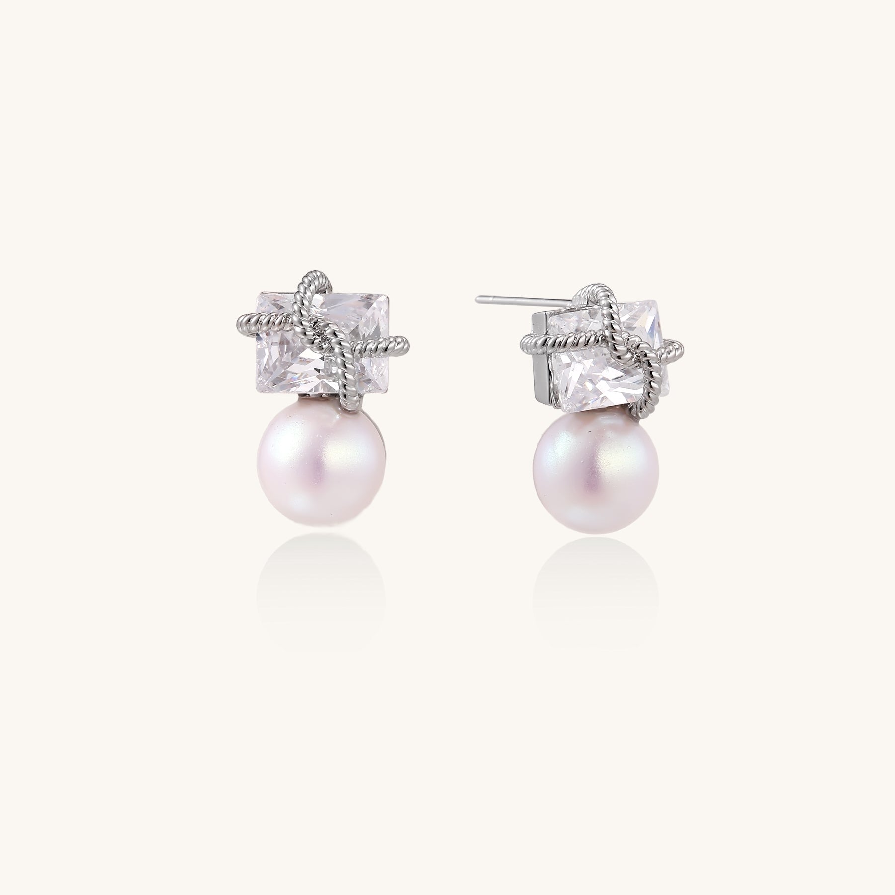 Gold-plated stud earrings with square crystal tops wrapped in twisted wire and freshwater pearl drops on white background