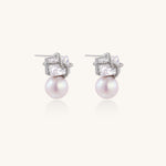 Gold-plated stud earrings with square crystal tops wrapped in twisted wire and freshwater pearl drops on white background