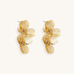 Layered gold-plated floral stud earrings with textured petals and crystal-accented centers on white background.