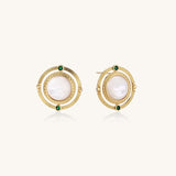 Close-up of gold-plated circular earrings with white mother-of-pearl centers and green zirconia accents on cream background.