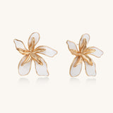 Large floral stud earrings with gold-plated brass petals and white enamel centers on neutral background