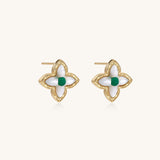 Dainty gold-plated quatrefoil stud earrings with white mother-of-pearl petals and green gemstone centers on beige background.