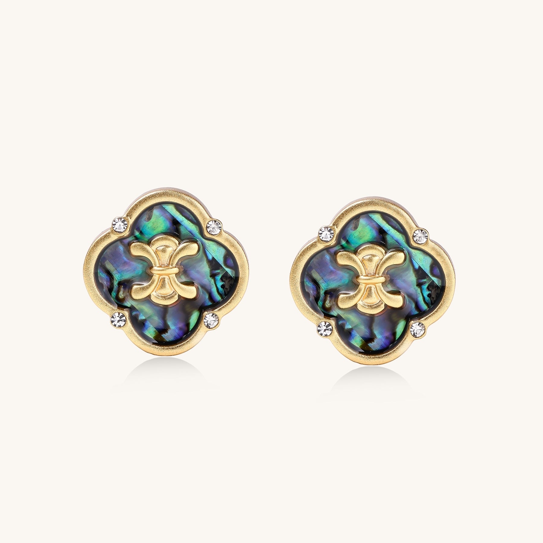 Gold-plated quatrefoil stud earrings featuring iridescent abalone shell centers with decorative motifs and crystal accents