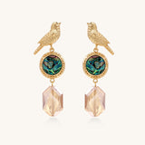Gold-plated bird dangle earrings with iridescent abalone shell discs and champagne crystal drops on white background.