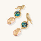 Gold-plated bird dangle earrings with iridescent abalone shell discs and champagne crystal drops on white background.