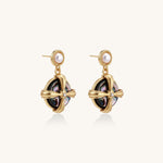 Gold-plated drop earrings with cross design framing iridescent abalone shell and pearl studs on neutral background.