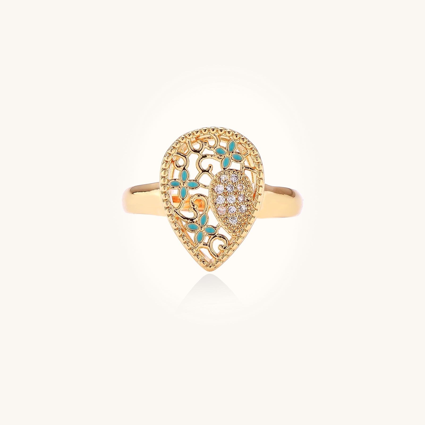 Gold-plated heart ring with turquoise enamel scrollwork and cubic zirconia stones on white background