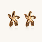 Large gold-plated flower earrings with brown enamel marbled petals on beige background, showing intricate floral design.