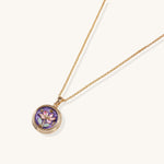 Gold-plated necklace with purple enamel pendant featuring pink floral design on white background
