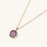 Gold-plated necklace with purple enamel pendant featuring pink floral design on white background