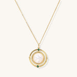 Gold-plated pendant necklace with circular orbital design, iridescent mother-of-pearl center and green zirconia accents