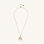 Gold-plated circular pendant featuring pink enamel rose with pearl accents and green leaf details on adjustable chain.
