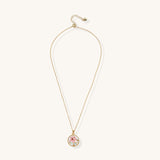 Gold-plated circular pendant featuring pink enamel rose with pearl accents and green leaf details on adjustable chain.
