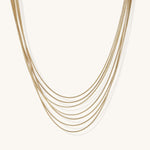 Multiple delicate gold-plated snake chains in graduated lengths on white background, adjustable layered necklace design.