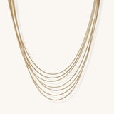 Multiple delicate gold-plated snake chains in graduated lengths on white background, adjustable layered necklace design.