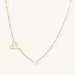 Dainty 14K gold-plated necklace with open heart pendant and white pearl bead on neutral background